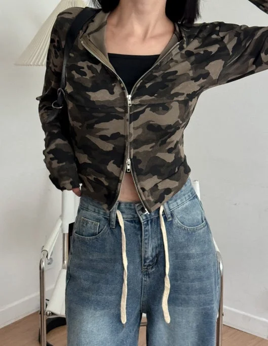 迷彩柄のジップアップパーカーに黒いチューブトップ、ドローストリング付きのデニムパンツを合わせた女性のカジュアルなファッションスナップです。ストリート感のあるスタイルが特徴的です。