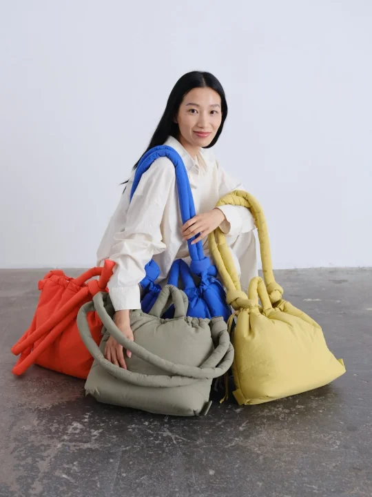 カラフルなバッグに囲まれた女性