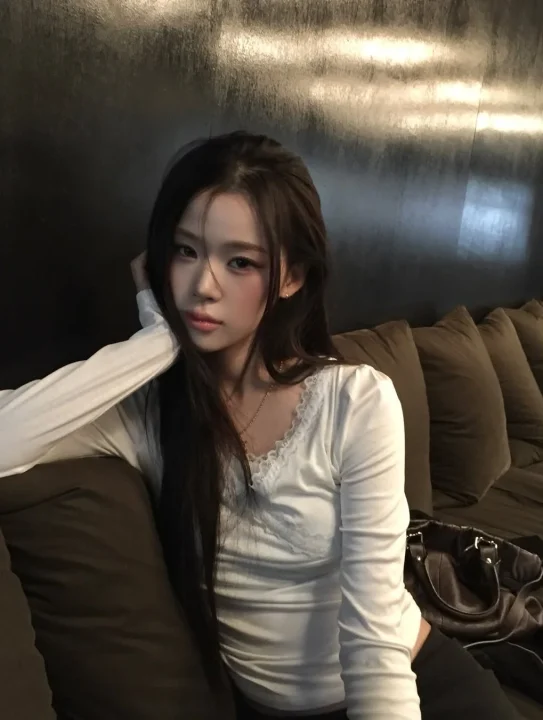 ソファに座りカメラを見つめるロングヘアの女性