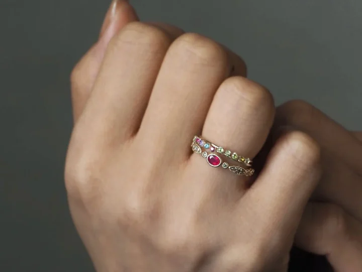 赤い楕円形の宝石と複数のカラーストーンが施されたLuceのリングを重ね付け