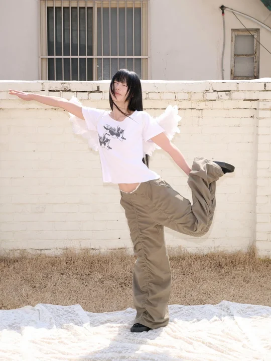 女性、ファッション、ポーズ、天使の羽、白いTシャツ、カーゴパンツ、屋外、壁、バランス、ストリートファッション、若者、個性
