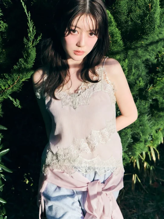 緑豊かな植物を背景に、自然光が当たる屋外で撮影された若い女性のポートレート