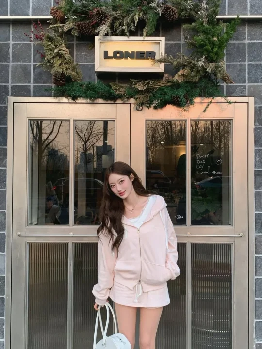 クリスマスリースで飾られた建物の前でポーズをとる女性