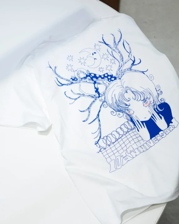 少女と木、星、月が描かれた10周年記念Tシャツ