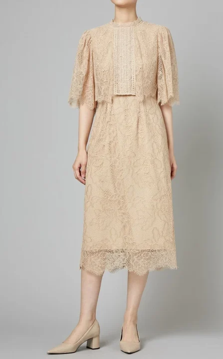 ベージュの総レースワンピースを着用した女性の全身像です。