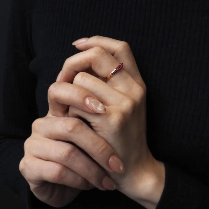 赤い宝石のローズゴールドリングを着用した手