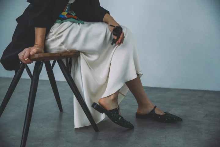 白いロングスカートと黒いジャケットの女性、足元はミュール