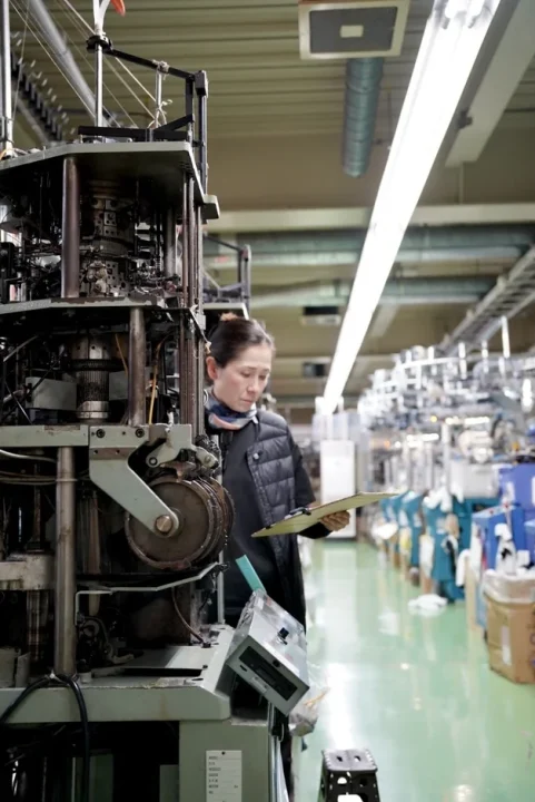 工場で編み機を点検する女性