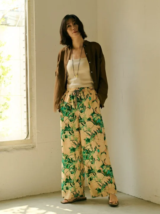 トロピカル柄ワイドパンツとシャツを着こなす女性