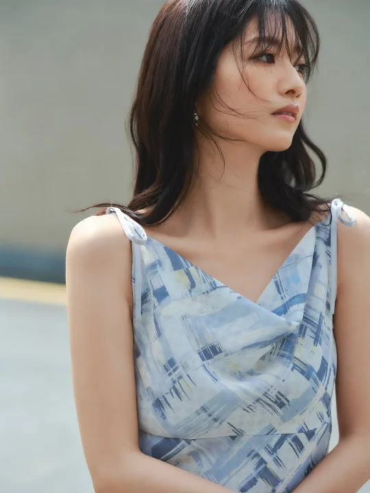 青い柄のドレスを着用した若い女性のポートレートです。風になびく髪と穏やかな表情で、横顔を見せています。夏の日の爽やかな雰囲気を感じさせます。