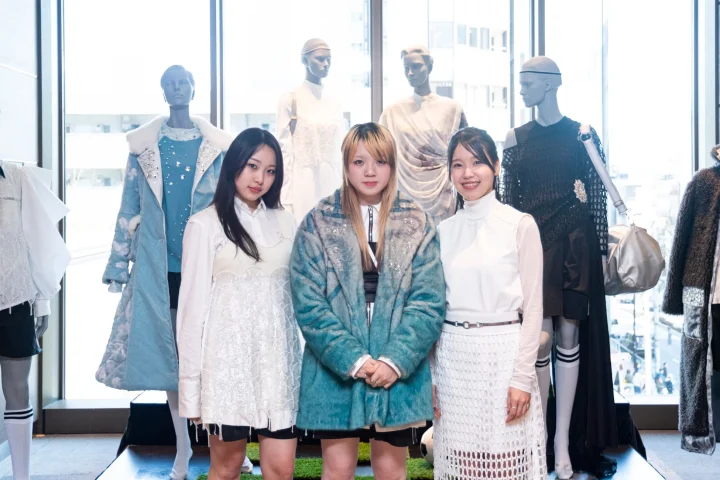 ファッション展示会場で笑顔で並んで立つ3人の女性