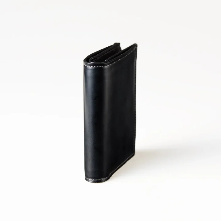 白い背景に立てて置かれた黒い革製の財布です