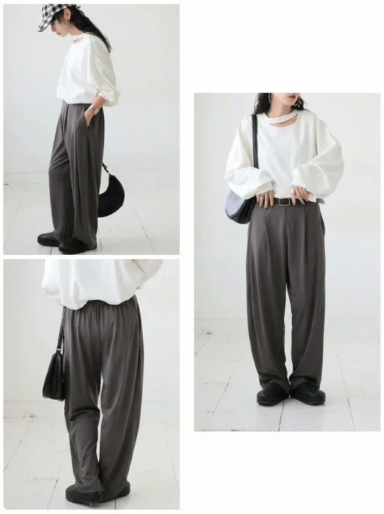 白いカットアウトネックのトップスとダークグレーのワイドパンツを合わせた女性