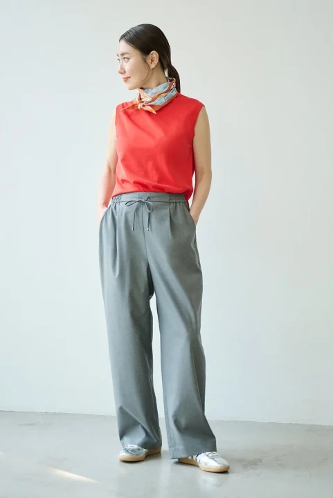 赤いノースリーブのトップスとグレーのワイドパンツを着用した女性