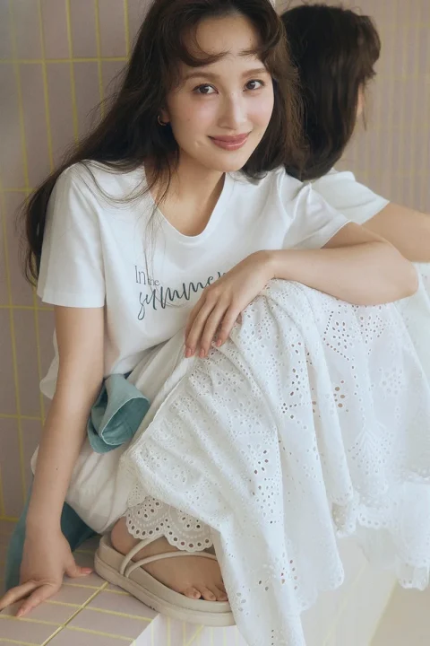 白いTシャツとレースのロングスカートを着て座って微笑む女性