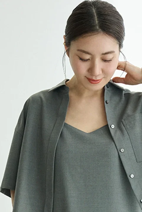 グレーグリーンのシャツとキャミソールを着用した女性