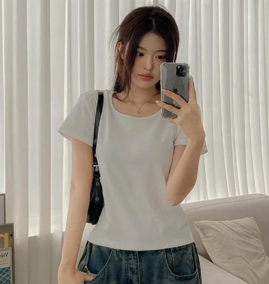 白いTシャツとデニムを着用した若い女性が、鏡越しにスマートフォンで自撮りをしているポートレート。