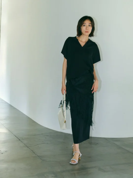 黒のVネックトップスとフリンジ付きロングスカートを着用したコーディネート