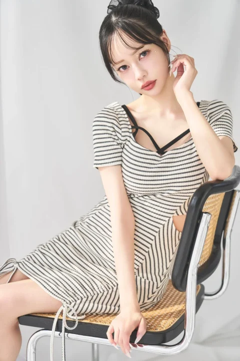 ストライプ柄のワンピースを着て椅子に座る女性