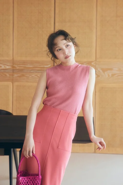ピンクのノースリーブトップスとスカートを着用した女性