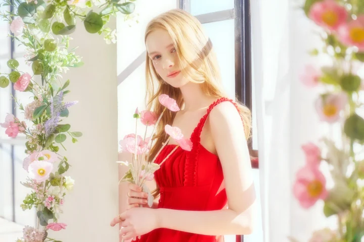 赤いドレスを着て花束を抱える金髪の女性