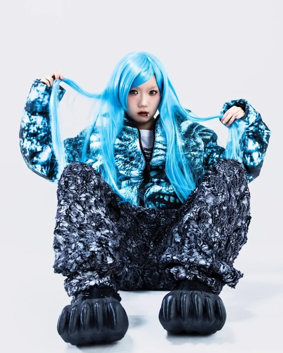 青い髪と個性的なパファージャケットの人物