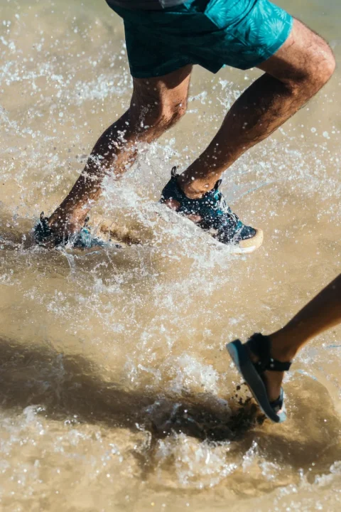 水しぶきを上げながら、男性が水辺を走っている様子