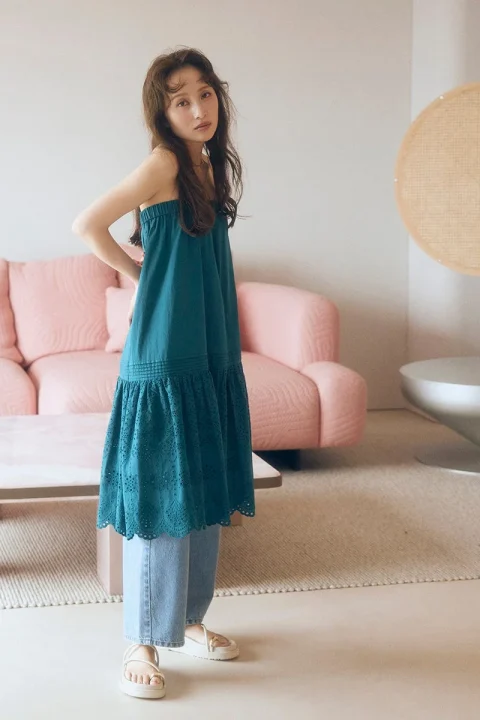 ターコイズブルーのチュニックとライトブルージーンズを着用した女性