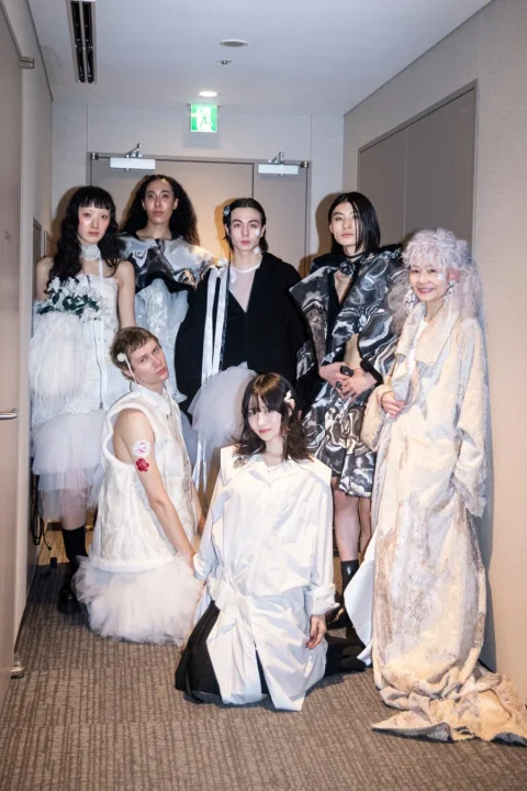 廊下でポーズをとるモデルたちの集合写真