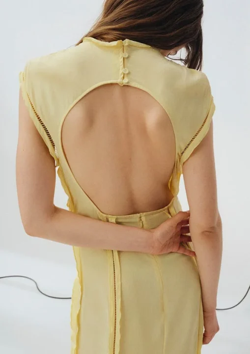 淡いイエローの背中が開いたドレスの女性の後ろ姿