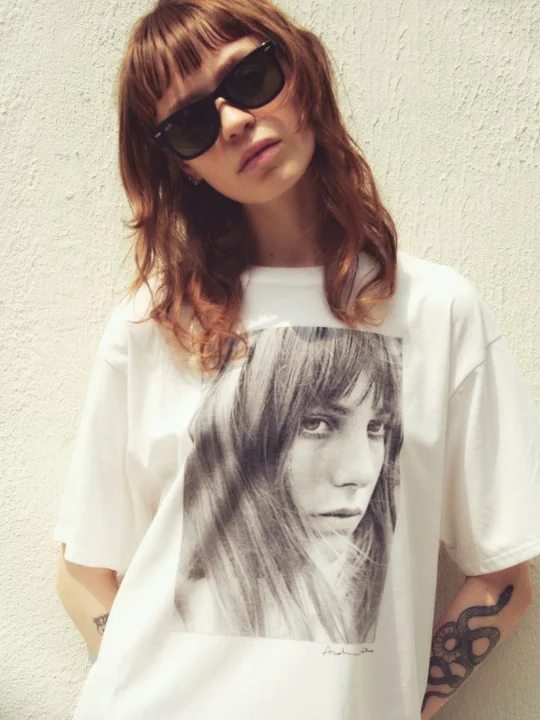 サングラスをかけた女性が、モノクロの女性の顔がプリントされたTシャツを着用