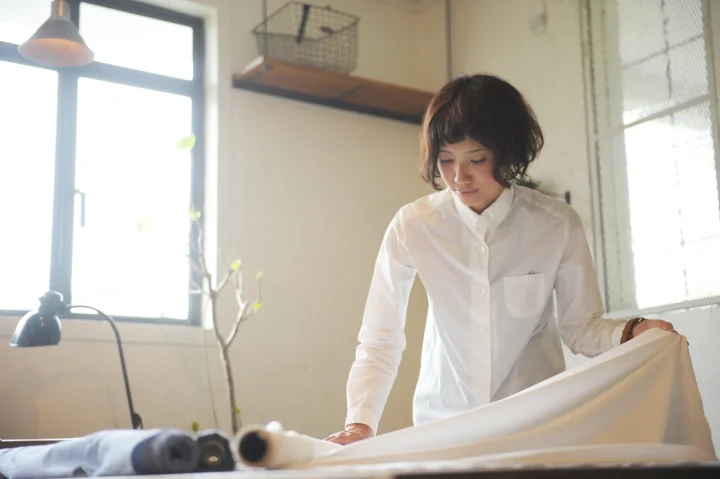 白いシャツを着た女性が生地を整える様子