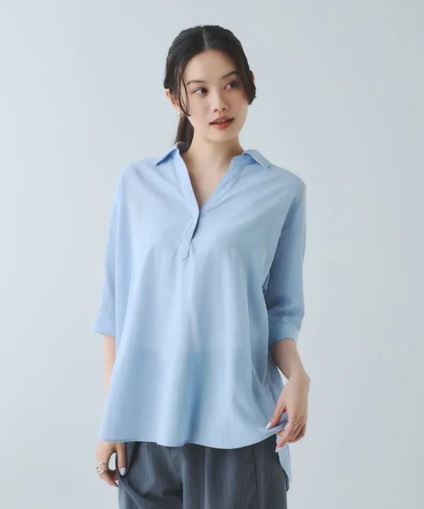 白い背景の前で、水色のVネックブラウスとグレーのストライプパンツを着用した若い女性のポートレートです。彼女は右方向を見ており、清潔感のあるシンプルなファッションスタイルが特徴的です。