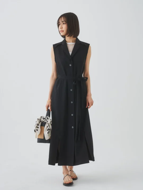 黒いノースリーブのベルト付きワンピースを着た女性