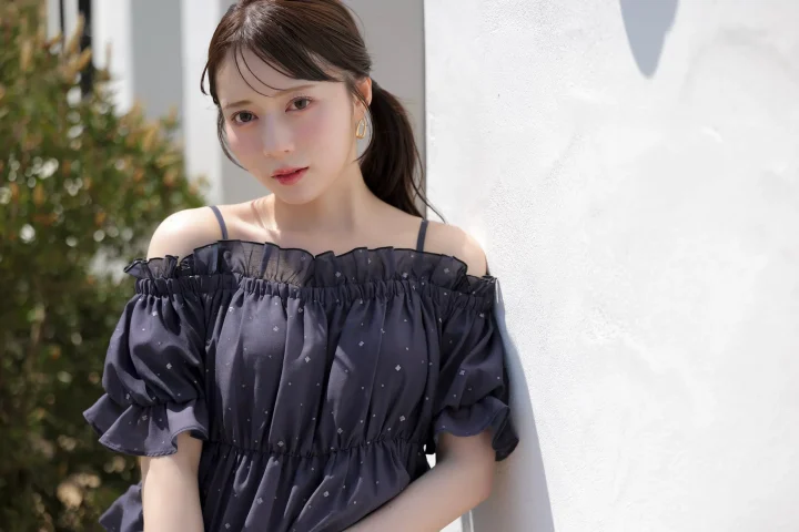 水瀬さららさんが着用するオフショルダーのトップスと白い壁を背景にしたコーディネート