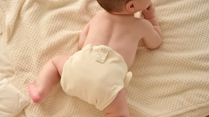布おむつを着用してうつ伏せに寝る赤ちゃん
