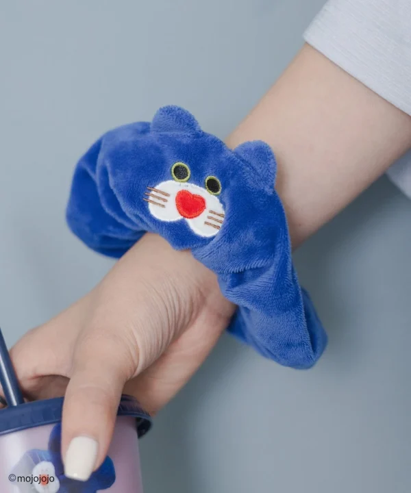 青い猫の顔がデザインされたシュシュを腕につけた人物
