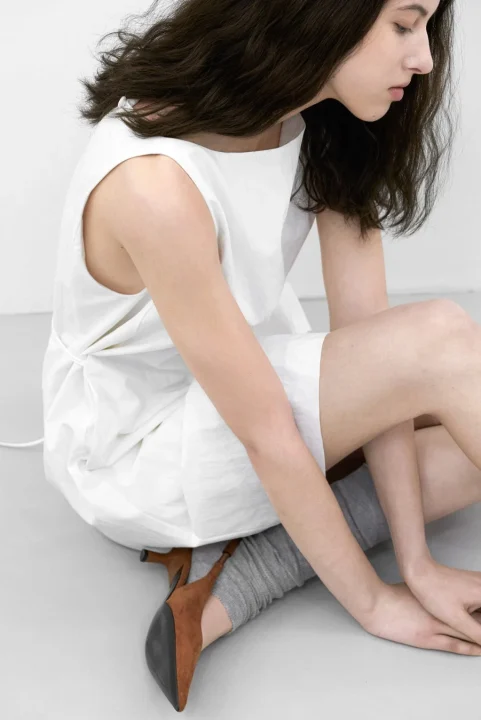 白いワンピースの女性モデルが座っている画像