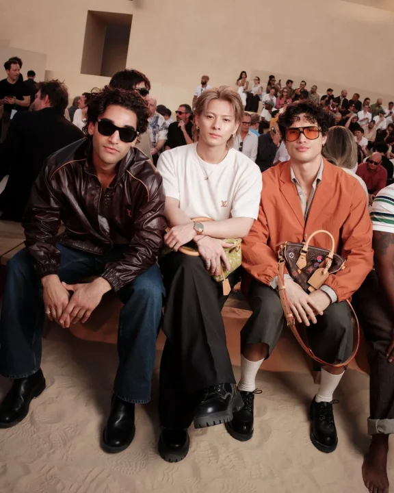ファッションイベント会場で座ってポーズをとる3人の男性
