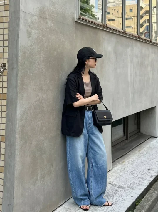 黒の半袖ジャケットとワイドデニムを合わせた女性