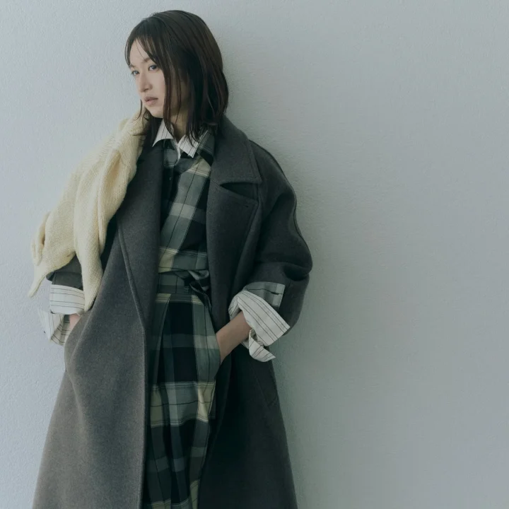 グレーのロングコートとチェック柄ワンピースの女性