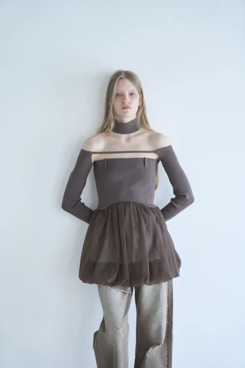 オフショルダーのニットトップスにチュール素材のミニスカートとダメージジーンズを合わせた女性モデル