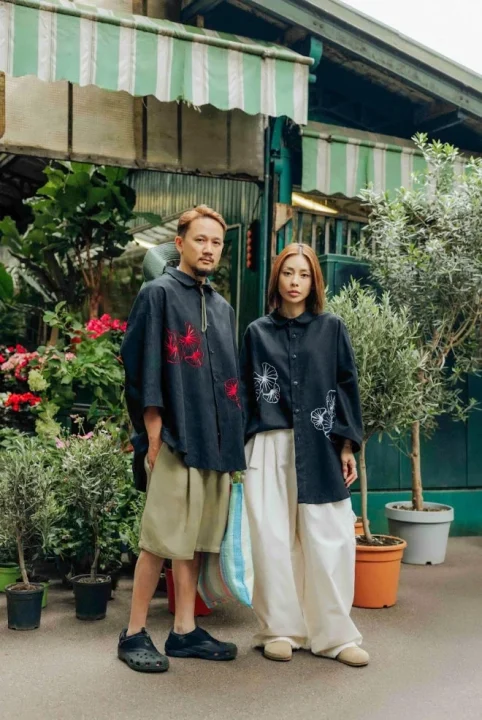 お揃いの黒いシャツに刺繍が施されたカジュアルな服装のアジア人カップル