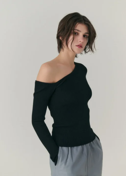黒いリブ編みオフショルダートップスとライトグレーパンツを着用した女性