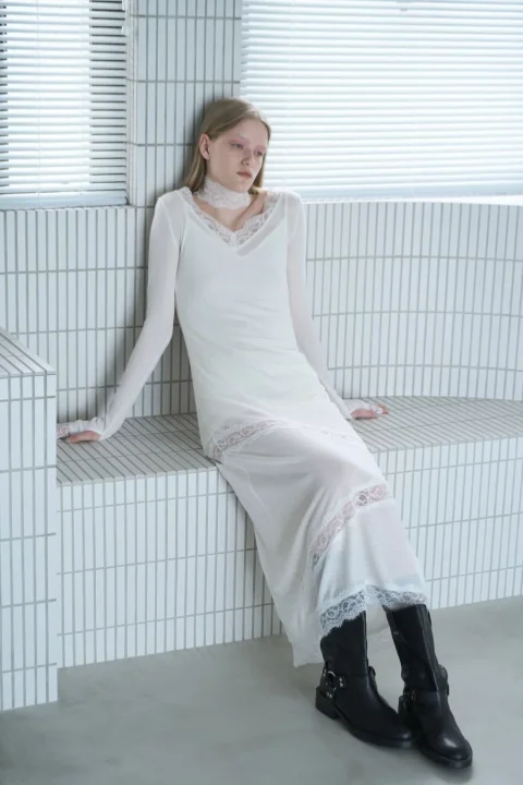 レースのトリムがあしらわれた白いロングドレスを着用した女性
