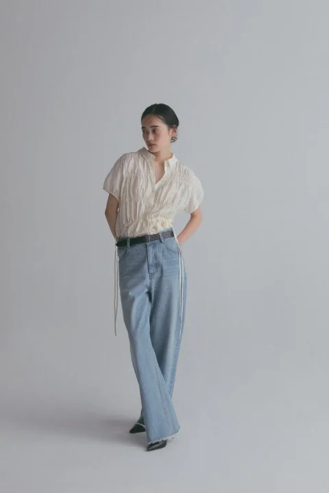 白いシャーリングトップスとワイドデニムの女性