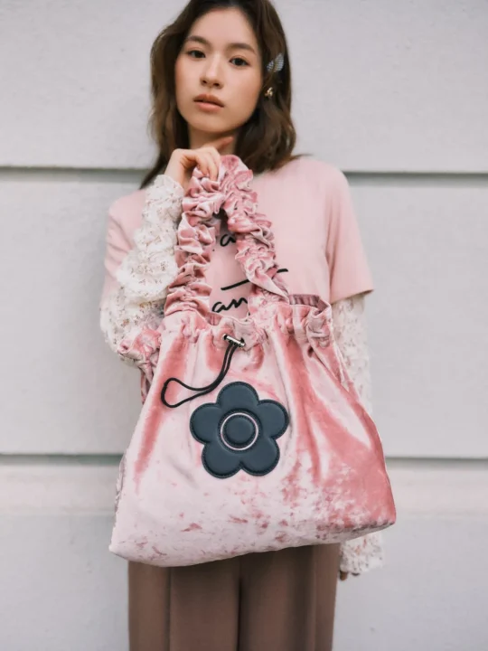 ピンクのベルベット製巾着バッグを持つ女性
