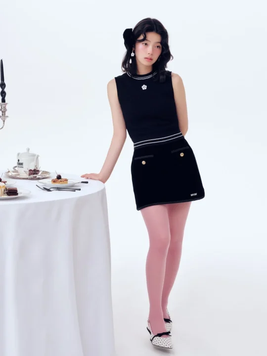 黒いノースリーブトップスとミニスカート、ピンクのタイツ