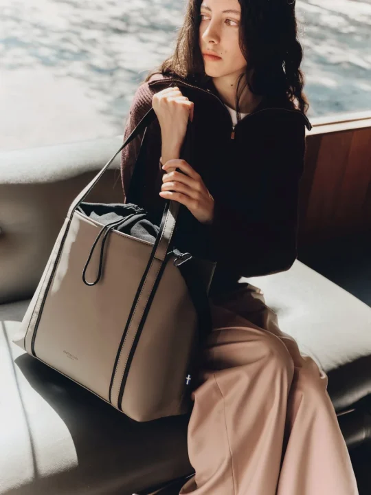 ソファに座り、ベージュのトートバッグを抱えた若い女性のポートレート。