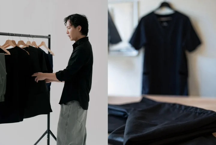 黒いシャツを着た男性がハンガーラックにかかった服を見ている